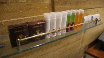 A glass shelf with various shower products, including bottles and boxes, against a textured wall.