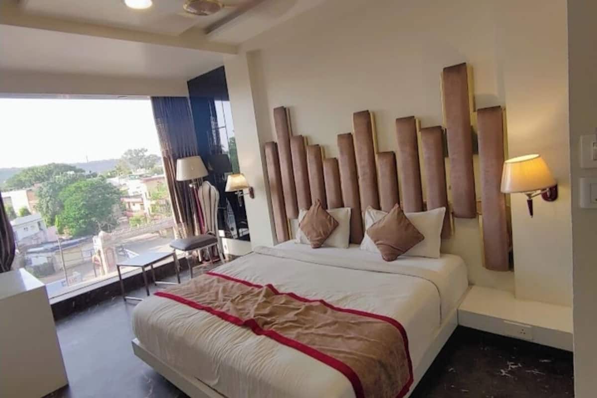 Ein modernes Hotelzimmer mit einem großen Bett, einem Schreibtisch und Blick auf die Stadt.