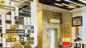 Un hall d’entrée avec un canapé marron, un comptoir d’accueil et un mur orné de motifs.