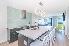A modern kitchen with a central island, a built-in oven, and a stainless steel range hood.
