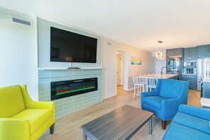 A modern living room with a flat-screen TV, a fireplace, and a dining area with a table and chairs. - Ocean Forest Updated 2 BR Modern Updates (Myrtle Beach)