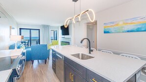 Een moderne keuken met een centraal eiland, een ingebouwde oven en een groot raam met uitzicht op zee.