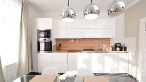 A modern kitchen with white cabinets, stainless steel appliances, and pendant lighting. - Central Sauna & Loft Apartments Leipzig (Leipzig)