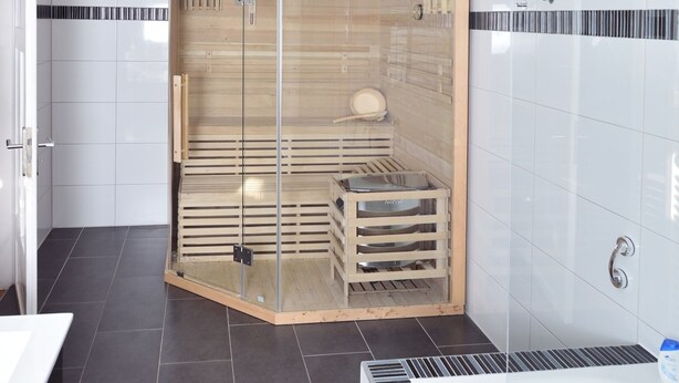 A modern bathroom with a glass-enclosed shower, a white bathtub, and dark tiled flooring. - Central Sauna & Loft Apartments Leipzig (Leipzig)