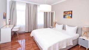 A modern hotel room with a large bed, a desk, and a chair. - Central Sauna & Loft Apartments Leipzig (Leipzig)