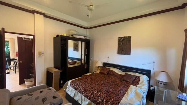 A bedroom with a bed, a wardrobe, a desk, and a chair.