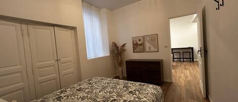 Een slaapkamer met een bed, een kledingkast en een bureau met een stoel.