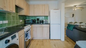 A compact kitchen with wooden cabinets, a white refrigerator, a microwave, and a coffee maker.