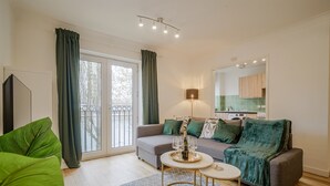 A modern living room with a grey sofa, a round coffee table, and a large green plant.