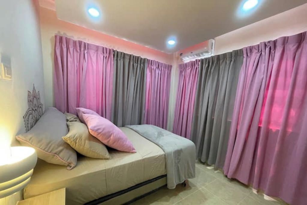 A bedroom with a bed, pillows, curtains, and a ceiling light.