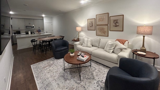 Una sala de estar moderna con un sofá, dos sillones, una mesa de centro y un comedor con sillas y una mesa.