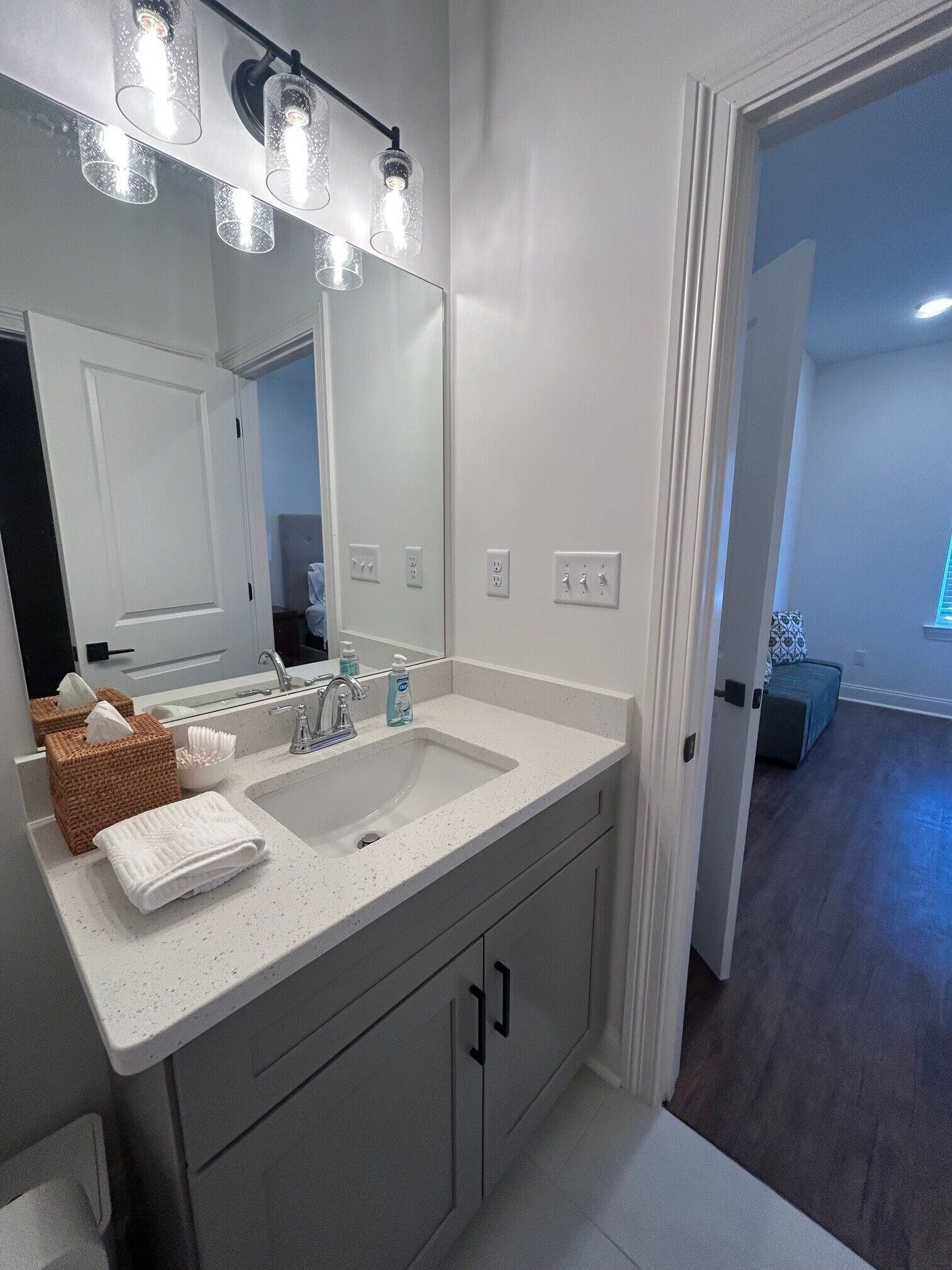 A modern bathroom with a double sink, a large mirror, and a light fixture above the mirror.