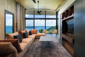 Ein modernes Wohnzimmer mit großem Fenster, einer Couch, einem Couchtisch und einem Fernseher.