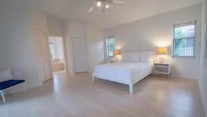 Une chambre à coucher avec un lit, des tables de chevet, un ventilateur de plafond et une fenêtre.