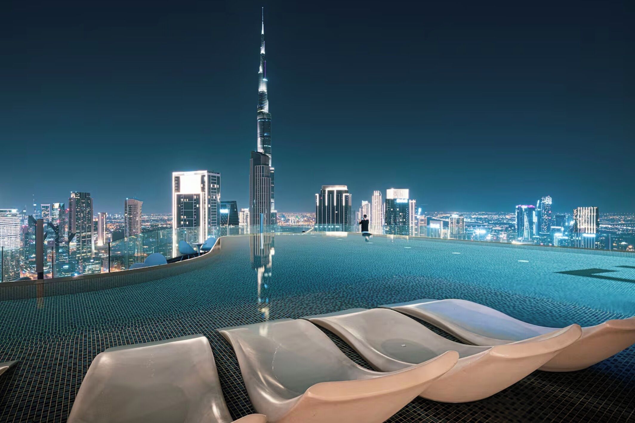 Ein Infinity-Pool auf dem Dach mit Blick auf die Stadtlandschaft, darunter ein markanter Wolkenkratzer.