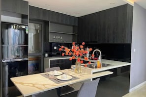 Eine moderne Küche mit Marmorarbeitsplatte, Edelstahlgeräten und einer Vase mit roten Blumen.