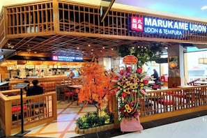 Ein Restaurant mit einem Schild, auf dem 'MARUKAME UDON & TEMPURA' steht, in einem Einkaufszentrum.