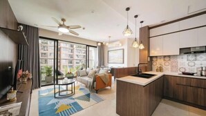 Eine moderne Wohnung mit Kücheninsel, Essbereich und Wohnzimmer mit Sofa und Fernseher.