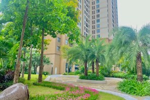 Un giardino curato con palme e un edificio sullo sfondo.