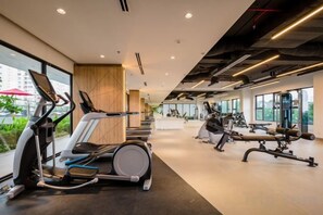 Ein modernes Fitnessstudio mit Cardiogeräten, Gewichtstrainern und großen Fenstern, die einen Blick ins Freie ermöglichen.