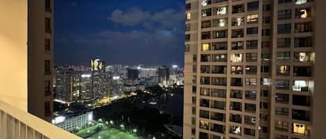 A high-rise building with multiple floors, a balcony, and a view of a cityscape at night.