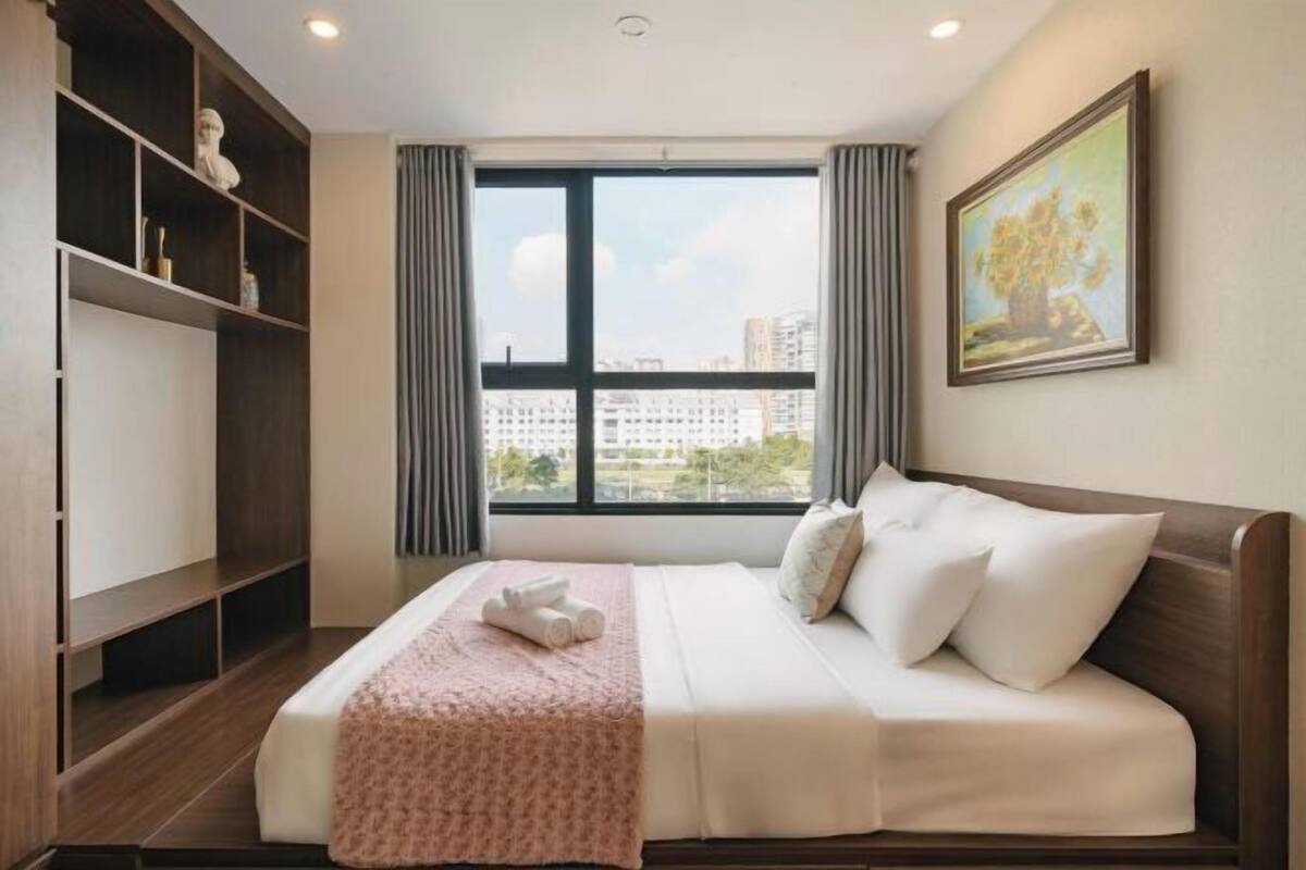Una habitación de hotel con cama, armario, ventana con vistas a la ciudad y un cuadro en la pared.