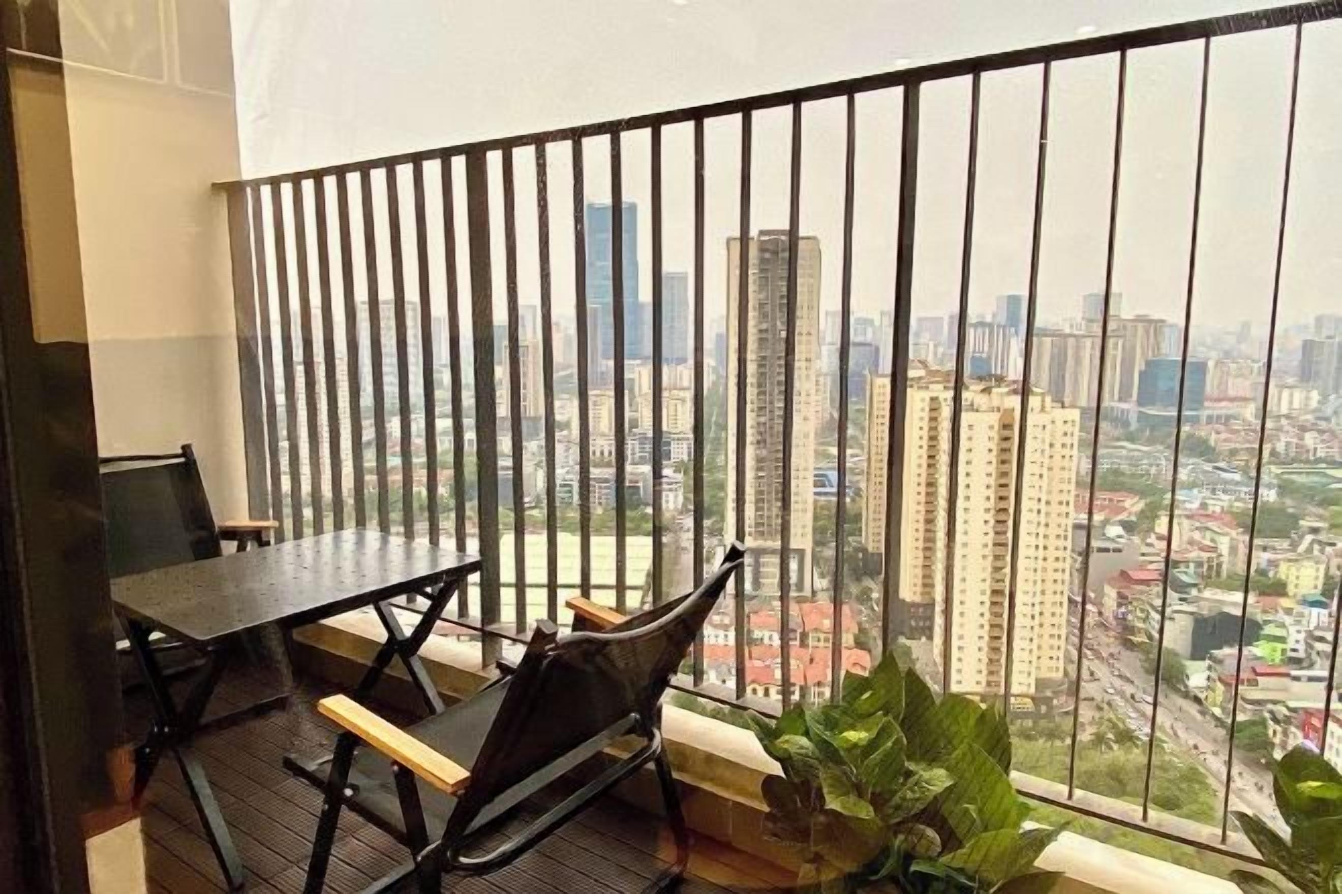 Un balcon donnant sur un paysage urbain, une table et deux chaises.