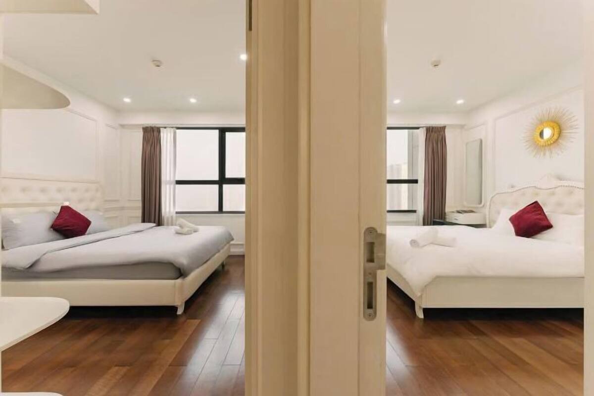 Una habitación de hotel con dos camas, un ventanal grande y un espejo con diseño de sol en la pared.