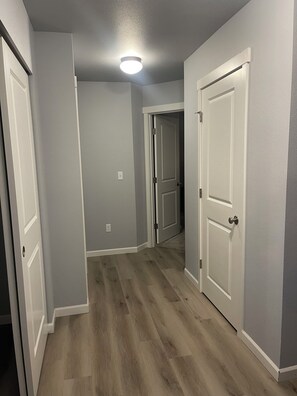 Un pasillo con suelo de madera, puertas blancas y una lámpara en el techo.