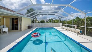 A covered swimming pool with a clear view of the sky and surrounding greenery. - Beautiful 3-bedroom Pool home on Canal in wonderful Rotonda West, Close to Beach (Rotonda West)