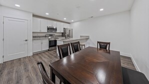 A modern kitchen with white cabinets, stainless steel appliances, and a wooden dining table with chairs. - Unwind in this stylish, newly renovated 1-bedroom suite near Topaz Lake. (Gardnerville)