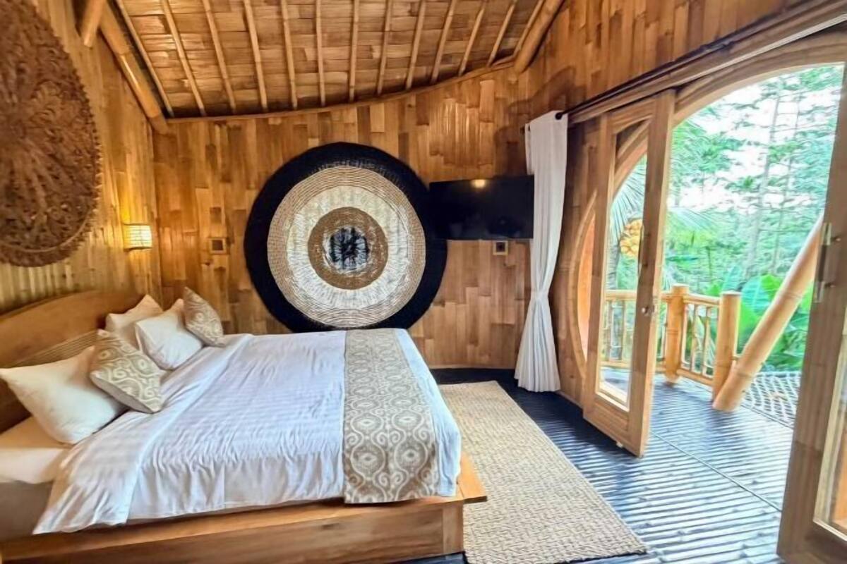 Une pièce en bois avec un lit, un téléviseur fixé au mur et un grand tapis rond.