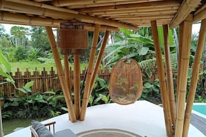 A bamboo pergola with a hanging wicker chair and a woven basket. - JinengBali Eco Lodge (Bali)