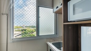Una cocina con ventana, un lavamanos y un microondas.