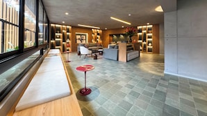 A modern hotel lobby with a seating area, a reception desk, and a large window with a view of the outside. - Luxury Stay Miraflores | Entre Marriott & Pullman (Miraflores)