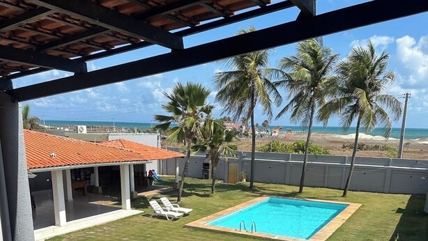 Un espace extérieur abrité comprenant une piscine, des chaises longues et une vue sur la plage.