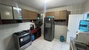 Une cuisine équipée d’une cuisinière à gaz, d’un réfrigérateur, d’un four à micro-ondes et d’un distributeur d’eau.