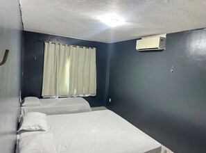 A room with a single bed, a window with curtains, an air conditioning unit, and a plain wall. - House in Cumbuco  (Caucaia)
