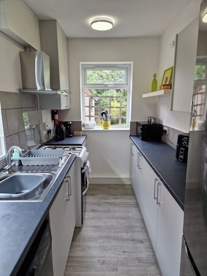 Een moderne keuken met een inbouwoven, een koffiezetapparaat en een raam met uitzicht op groen.