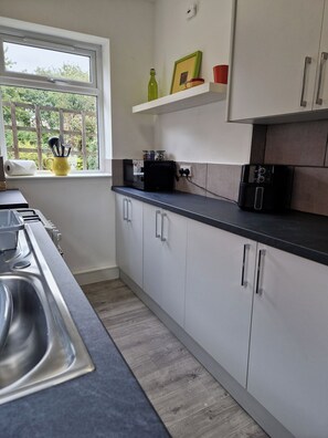 A kitchen with a window, a sink, cabinets, and a countertop.