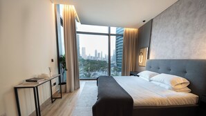 Una habitación de hotel moderna con una cama grande, una mesita de noche y vistas a la ciudad. Tiene una ventana con cortinas.