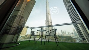Un balcón con vistas al Burj Khalifa, dos sillas, una mesita y un adorno esférico.