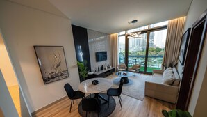 Una sala de estar moderna con comedor, un sofá, un televisor y vistas de la ciudad.