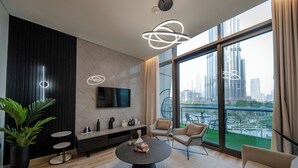 Una sala moderna con una mesa redonda, un televisor montado en la pared y un balcón con vistas a la ciudad.