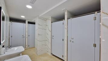 Een badkamer met een grote spiegel, twee wastafels en marmeren wanden.