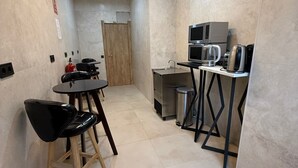 A compact kitchen with a dining area, equipped with a microwave, coffee maker, and a small sink. - Velvet Hostel Business (Madrid)