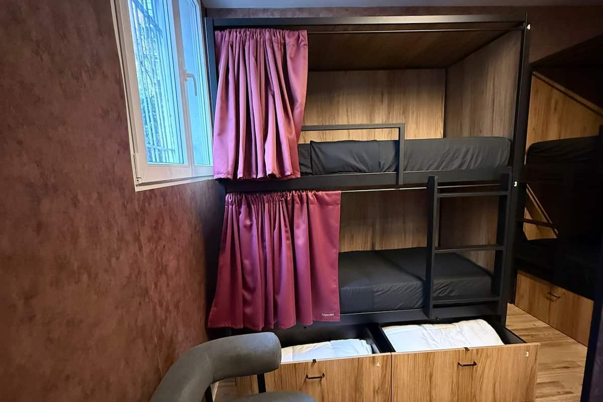 A compact room with bunk beds, a desk, and a window with curtains.