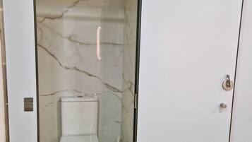Un baño con inodoro, bidé y un armario blanco.