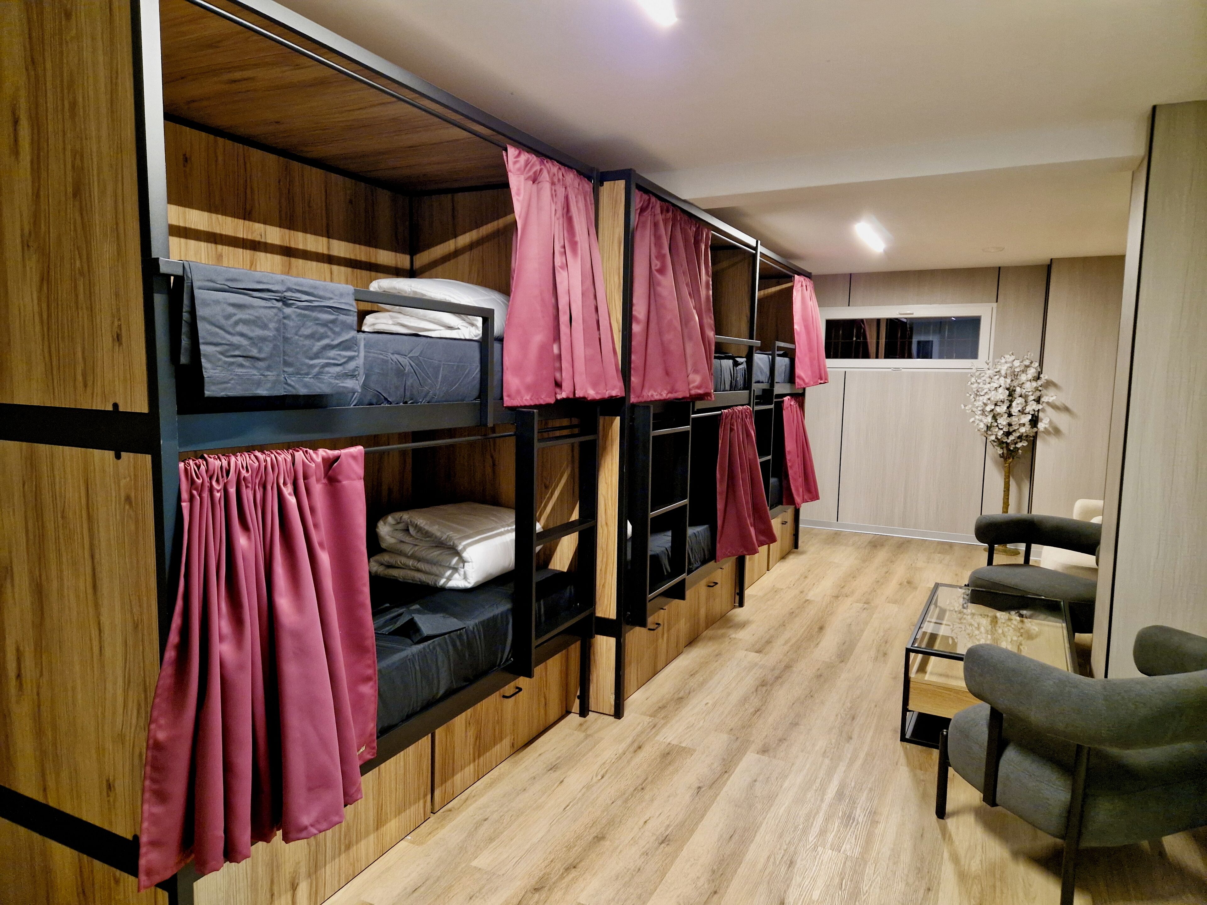 A dormitory room with bunk beds, a small table, and a chair.