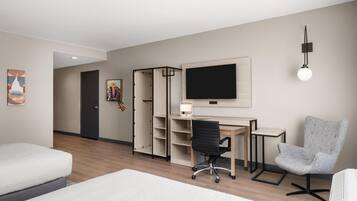 A hotel room with a bed, a desk with a computer, a chair, a TV, and a wardrobe.